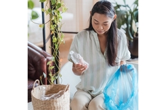 Image A woman recycling an empty plastic bottle.